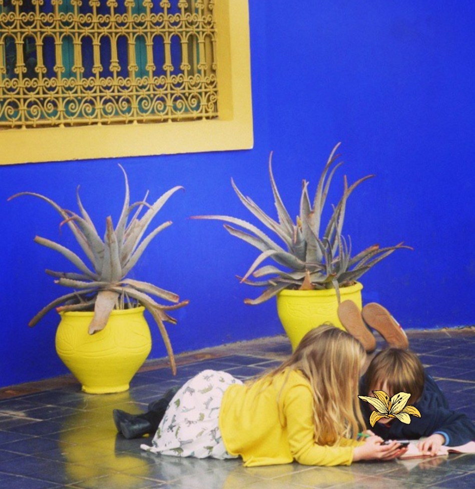children colouring in against a beautiful blue wall in Yves St Laurent's garden, Morocco